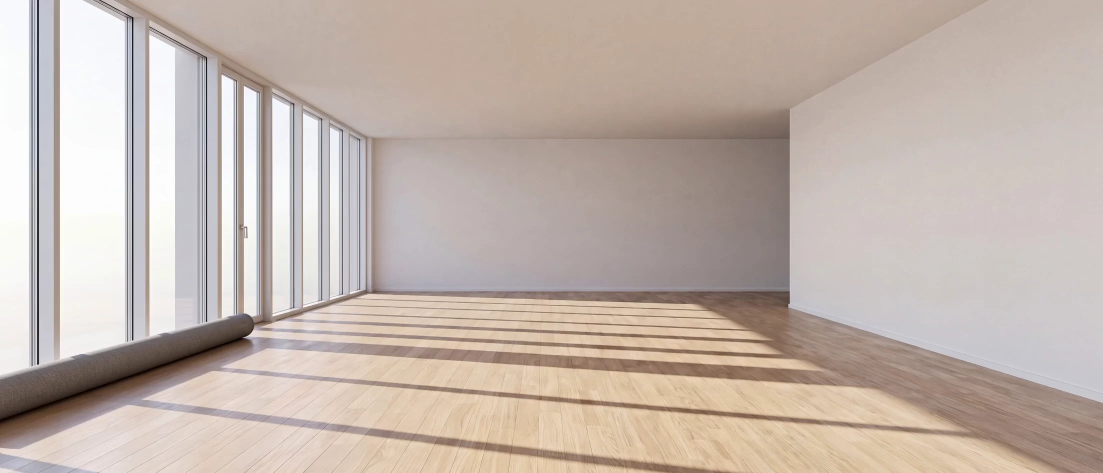 Ein leerer Büroraum an einer Fensterfront richtet sich ein: Teppich, zwei Schreibtische mit Stühlen, Sideboard mit zwei Druckern, Regal und Zimmerpflanze